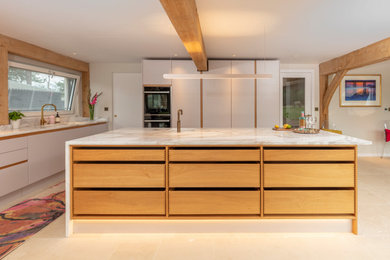 This is an example of a modern kitchen in Surrey with an integrated sink, flat-panel cabinets and an island.
