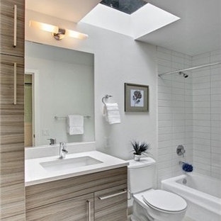 Foto di una stanza da bagno con doccia minimalista di medie dimensioni con lavabo sottopiano, ante lisce, ante grigie, top in quarzo composito, pareti grigie, pavimento in gres porcellanato, vasca da incasso, WC a due pezzi, piastrelle bianche, piastrelle in ceramica, pavimento grigio, doccia alcova, doccia con tenda e top bianco