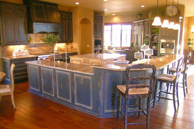 Inspiration for a large french country u-shaped bamboo floor and brown floor eat-in kitchen remodel in Denver with an undermount sink, raised-panel cabinets, distressed cabinets, granite countertops, beige backsplash, slate backsplash, stainless steel appliances, two islands and beige countertops