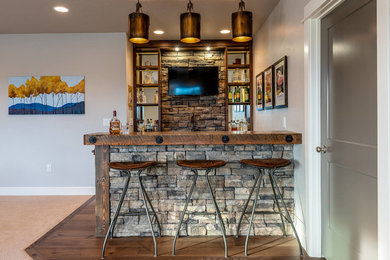 Photo of a country galley wet bar in Other with open cabinets, wood benchtops, grey splashback, stone tile splashback, medium hardwood floors, brown floor and brown benchtop.