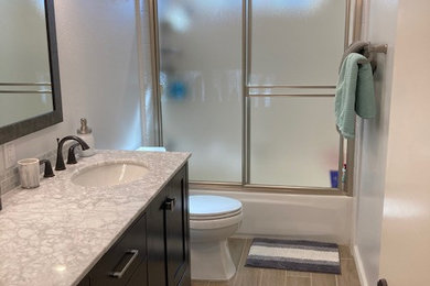 Example of a mid-sized trendy kids' gray tile and marble tile ceramic tile, brown floor and double-sink bathroom design in Los Angeles with shaker cabinets, black cabinets, a two-piece toilet, blue walls, an undermount sink, marble countertops, gray countertops and a freestanding vanity