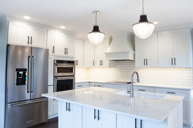Large transitional l-shaped dark wood floor and brown floor eat-in kitchen photo in Other with an undermount sink, recessed-panel cabinets, white cabinets, quartz countertops, white backsplash, subway tile backsplash, stainless steel appliances and an island