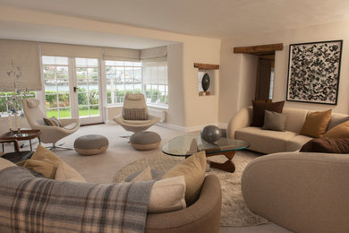 Large coastal open plan living room in Devon with beige walls, carpet, a wood burning stove and beige floors.
