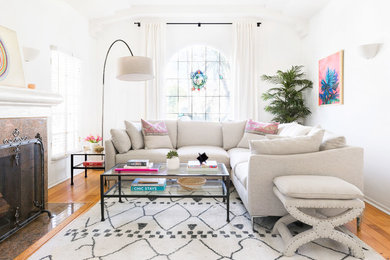 Example of a transitional medium tone wood floor and brown floor living room design in Los Angeles with white walls, a standard fireplace and a tile fireplace