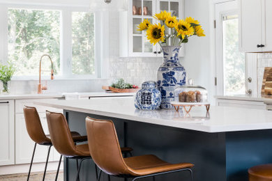 Inspiration for a mid-sized transitional u-shaped eat-in kitchen in Boston with a double-bowl sink, glass-front cabinets, blue cabinets, quartz benchtops, white splashback, ceramic splashback, stainless steel appliances, dark hardwood floors, with island, brown floor and white benchtop.