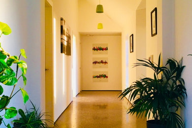 他の地域にある中くらいなコンテンポラリースタイルのおしゃれな廊下 (白い壁、コンクリートの床、グレーの床、三角天井、パネル壁) の写真