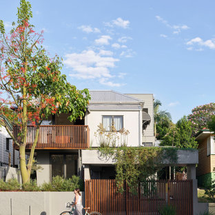 Inspiration for a contemporary two-storey stucco beige house exterior in Brisbane with a metal roof, a grey roof and board and batten siding.