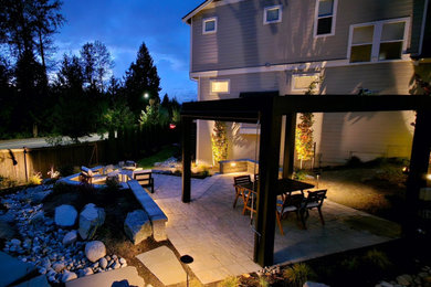 This is an example of a backyard concrete paver landscaping in Seattle with a pergola.