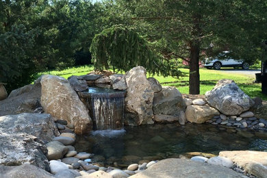 Inspiration for a large traditional front yard stone pond in Miami.