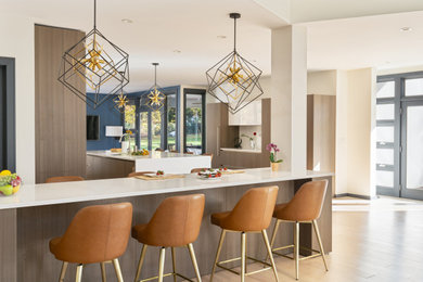 Example of a large trendy l-shaped light wood floor eat-in kitchen design in New York with flat-panel cabinets, medium tone wood cabinets, white backsplash, two islands and white countertops