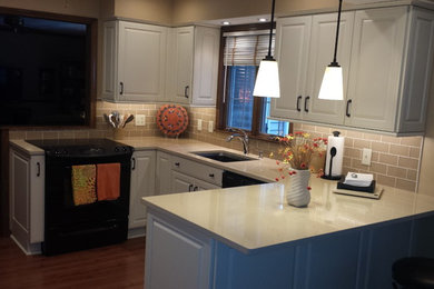 Mid-sized elegant u-shaped medium tone wood floor eat-in kitchen photo in Other with an undermount sink, raised-panel cabinets, white cabinets, quartz countertops, a peninsula, beige backsplash, subway tile backsplash and black appliances