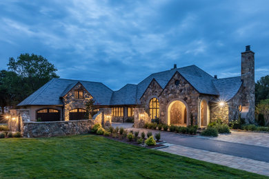 Large french country gray two-story stone exterior home photo in Other with a tile roof and a gray roof