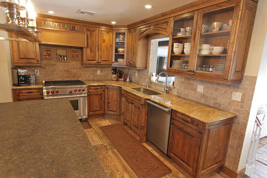 Kitchen - mid-sized traditional l-shaped medium tone wood floor and brown floor kitchen idea in Other with an undermount sink, raised-panel cabinets, granite countertops, beige backsplash, stone tile backsplash, stainless steel appliances, an island and dark wood cabinets