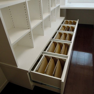 Photo of a small modern home studio in Other with white walls, plywood flooring, a built-in desk and brown floors.