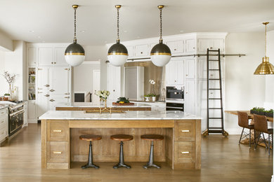 Large transitional medium tone wood floor and brown floor kitchen photo in Denver with a drop-in sink, recessed-panel cabinets, white cabinets, paneled appliances, two islands and granite countertops