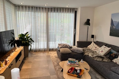 Mittelgroßes, Offenes Modernes Wohnzimmer mit beiger Wandfarbe, Keramikboden, freistehendem TV und braunem Boden in Köln