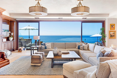 Large transitional open concept beige floor, limestone floor and tray ceiling living room photo in Orange County with a standard fireplace, a wood fireplace surround, a wall-mounted tv and beige walls