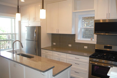 Exempel på ett litet amerikanskt kök, med en enkel diskho, skåp i shakerstil, skåp i ljust trä, granitbänkskiva, grått stänkskydd, stänkskydd i glaskakel, rostfria vitvaror, mellanmörkt trägolv och en köksö