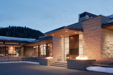 Diseño de fachada de casa beige y marrón minimalista extra grande con revestimiento de piedra, tejado a cuatro aguas y tejado de metal