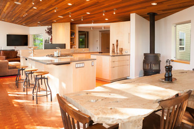 Large modern u-shaped open plan kitchen in Seattle with an undermount sink, brown floor, flat-panel cabinets, light wood cabinets, panelled appliances, medium hardwood floors, grey benchtop, with island and solid surface benchtops.