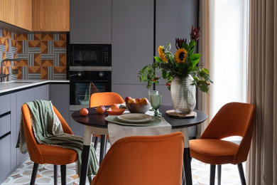 サンクトペテルブルクにあるコンテンポラリースタイルのおしゃれなキッチン (グレーのキャビネット、クオーツストーンカウンター、オレンジのキッチンパネル、シルバーの調理設備、磁器タイルの床、白いキッチンカウンター) の写真
