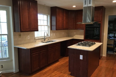 Kitchen pantry - large traditional u-shaped light wood floor kitchen pantry idea in DC Metro with an undermount sink, raised-panel cabinets, brown cabinets, granite countertops, beige backsplash, cement tile backsplash, black appliances and an island