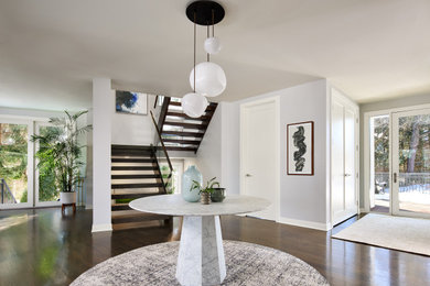 Example of a huge trendy dark wood floor and brown floor foyer design in Chicago with white walls