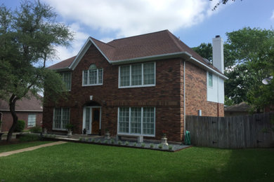 Large traditional red two-story brick house exterior idea in Austin with a hip roof and a shingle roof