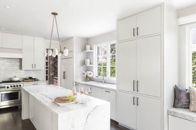Trendy dark wood floor and brown floor kitchen photo in Austin with an undermount sink, flat-panel cabinets, white cabinets, white backsplash, ceramic backsplash, stainless steel appliances and an island