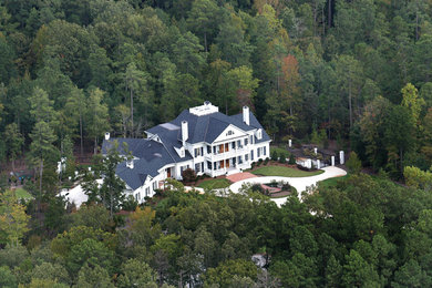 Example of a classic white three-story brick gable roof design in Raleigh