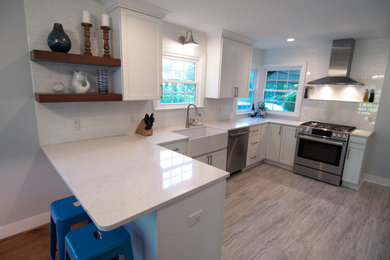 Inspiration for a mid-sized transitional u-shaped ceramic tile and beige floor eat-in kitchen remodel in Grand Rapids with a farmhouse sink, shaker cabinets, white cabinets, quartz countertops, white backsplash, subway tile backsplash, stainless steel appliances, a peninsula and white countertops