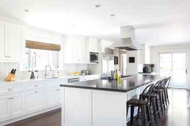 Kitchen - transitional dark wood floor kitchen idea in Santa Barbara with an undermount sink, shaker cabinets, white cabinets, white backsplash, stainless steel appliances and an island