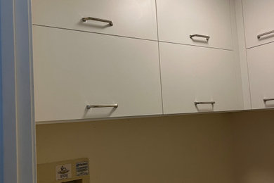 Foto de lavadero en L actual con armarios con paneles lisos, puertas de armario blancas y lavadora y secadora juntas