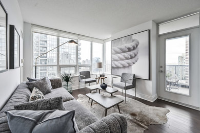 Example of a mid-sized trendy enclosed laminate floor and brown floor living room design in Toronto with gray walls, no fireplace and no tv