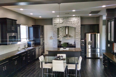 Example of a mid-sized trendy l-shaped ceramic tile eat-in kitchen design in Phoenix with a drop-in sink, recessed-panel cabinets, black cabinets, marble countertops, white backsplash, stainless steel appliances, an island and subway tile backsplash