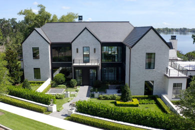 Inspiration for a huge transitional white three-story stone house exterior remodel in Orlando with a shingle roof and a black roof