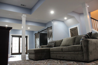 Immagine di un grande soggiorno industriale chiuso con sala giochi, pareti blu, pavimento in laminato, TV a parete e pavimento marrone