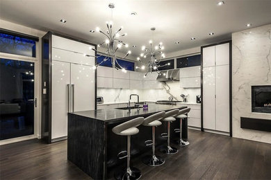 Large trendy l-shaped medium tone wood floor and brown floor kitchen photo in Other with an undermount sink, flat-panel cabinets, white cabinets, gray backsplash, marble backsplash and paneled appliances