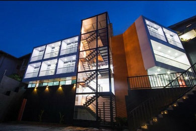 Example of a mid-sized minimalist multicolored three-story flat roof design in Other