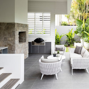 Beach style patio in Sunshine Coast with with fireplace, tile and a roof extension.