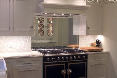 Enclosed kitchen - small transitional l-shaped medium tone wood floor enclosed kitchen idea in San Francisco with a farmhouse sink, white cabinets, marble countertops, white backsplash, mosaic tile backsplash, stainless steel appliances and an island