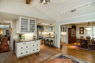 Example of a large classic u-shaped medium tone wood floor open concept kitchen design in Dallas with an undermount sink, raised-panel cabinets, white cabinets, granite countertops, white backsplash, subway tile backsplash, stainless steel appliances and an island