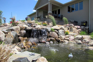 This is an example of a large traditional backyard stone water fountain landscape in Other.
