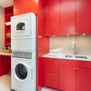 プロビデンスの中サイズのコンテンポラリースタイルのおしゃれな洗濯室 (アンダーカウンターシンク、フラットパネル扉のキャビネット、赤いキャビネット、クオーツストーンカウンター、グレーの壁、磁器タイルの床、上下配置の洗濯機・乾燥機、白いキッチンカウンター、白い床) の写真