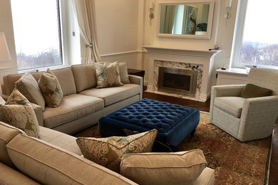 Esempio di un soggiorno classico chiuso con pareti bianche, camino classico, cornice del camino in intonaco e pavimento marrone