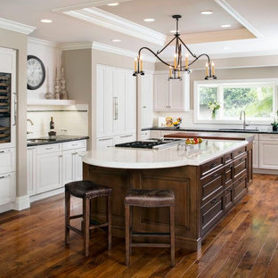 Design ideas for a large transitional l-shaped kitchen pantry in Orange County with a double-bowl sink, flat-panel cabinets, white cabinets, granite benchtops, white splashback, subway tile splashback, stainless steel appliances, dark hardwood floors and with island.