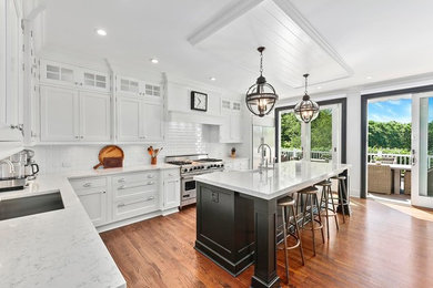 Large beach style l-shaped medium tone wood floor and brown floor kitchen photo in New York with shaker cabinets, white cabinets, white backsplash, subway tile backsplash, stainless steel appliances, an island and quartzite countertops
