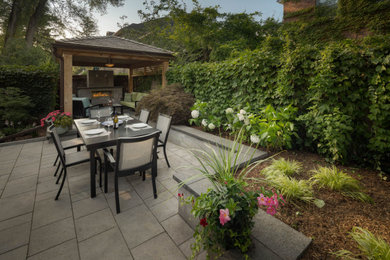 Inspiration for a mid-sized contemporary backyard garden in Toronto with a retaining wall and natural stone pavers.