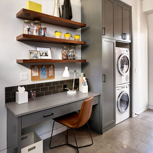 ポートランドの大きいコンテンポラリースタイルのおしゃれな家事室 (シェーカースタイル扉のキャビネット、グレーのキャビネット、コンクリートカウンター、白い壁、磁器タイルの床、上下配置の洗濯機・乾燥機) の写真