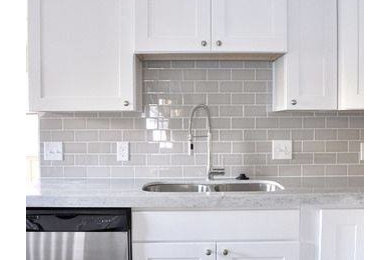 Enclosed kitchen - large transitional l-shaped concrete floor and gray floor enclosed kitchen idea in Orange County with an undermount sink, shaker cabinets, white cabinets, solid surface countertops, gray backsplash, stainless steel appliances, no island and ceramic backsplash